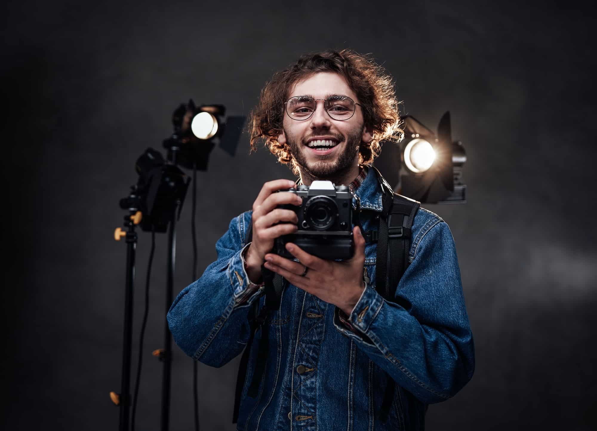 young-photographer-holds-a-camera-studio-portrait-with-lighting-equipment-in-the-background.jpg
